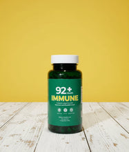 Load image into Gallery viewer, 92+ Immune Sea Moss Capsules bottle on wooden surface with yellow background
